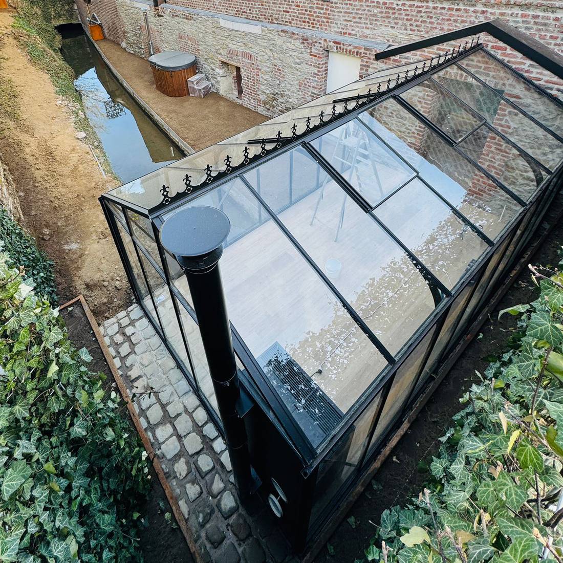 Elegant aluminiumväxthus med tydlig entré och omsorgsfullt planerad omgivning