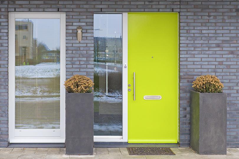 Byggnadens ytterdörrar i grön färg med en inbyggd brevlåda