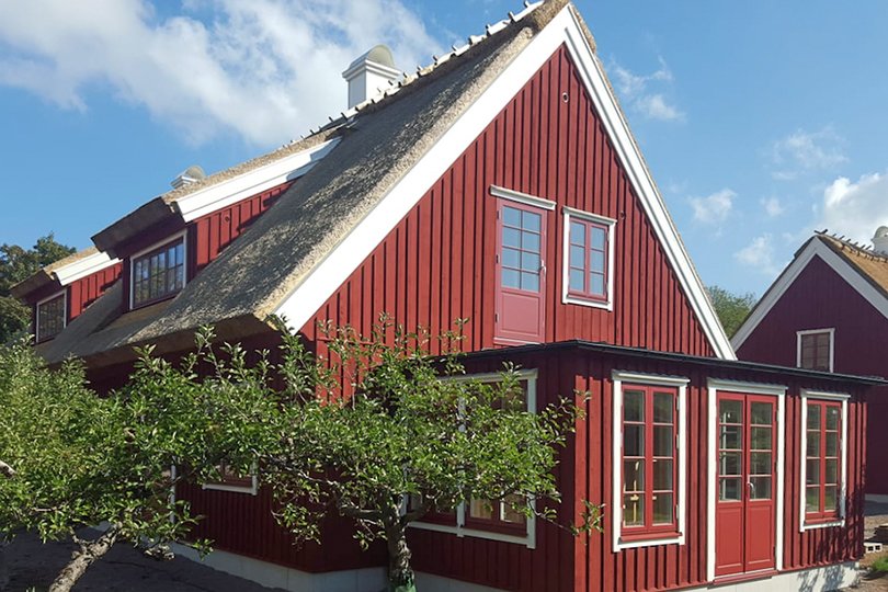 röd trävåning i två våningar med halmtak och fönster av god kvalitet